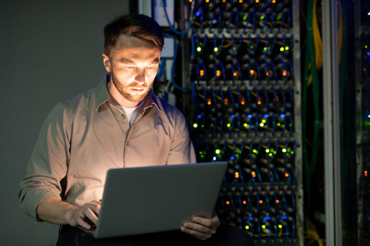 A tech looking at a laptop while in a server room