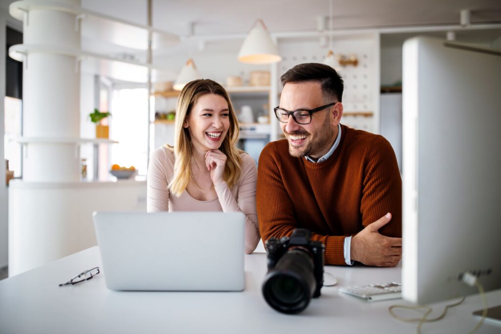 Two people looking over a laptop with a camera next to it