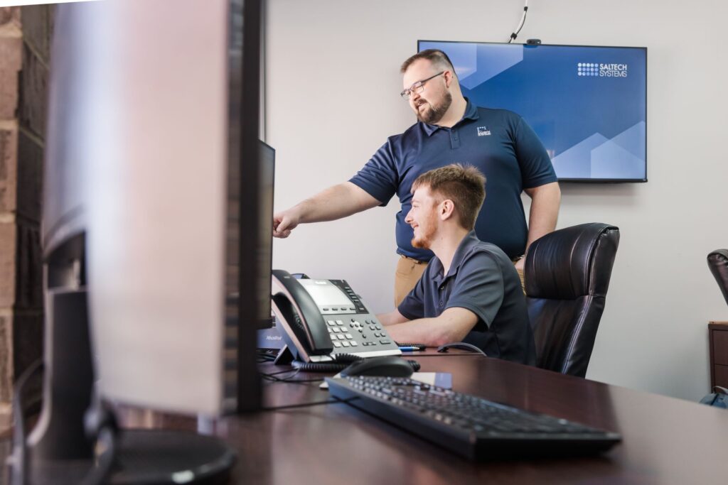 A Saltech employee pointing out something on the monitor of a coworker