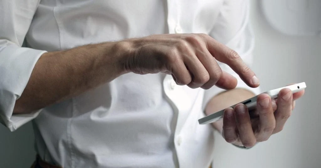 A zoomed in picture on a man's hands using a cell phone