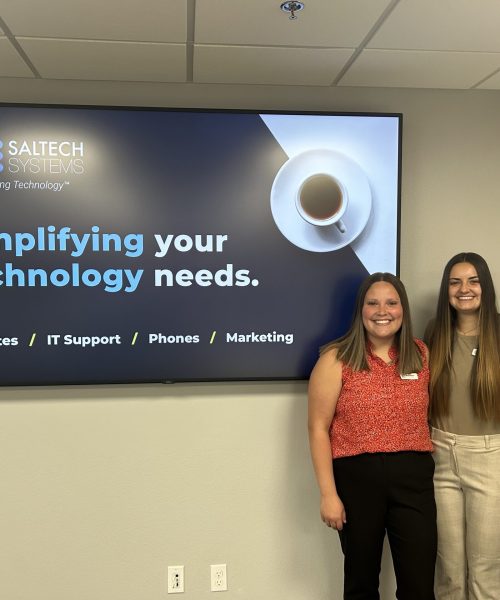 Saltech employees posing in front of a tv with info on Saltech